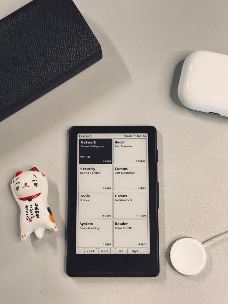 Biscuit firmware on the Xteink X4 — a tile dashboard with Network, Recon, Security, Comms, Tools, Games, System and Reader app categories